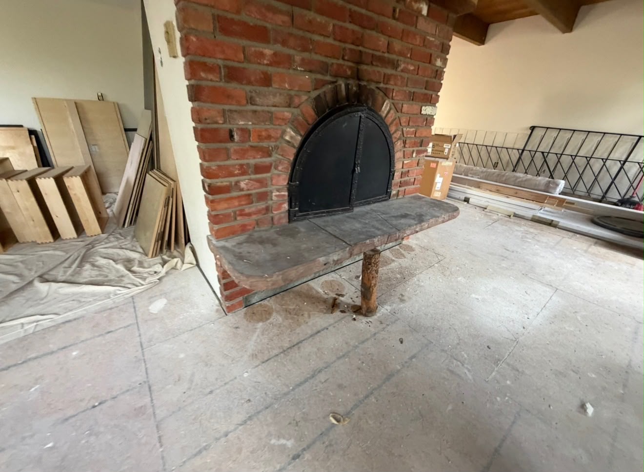Cracked brick fireplace hearth propped up with a wooden post before chimney and fireplace repair