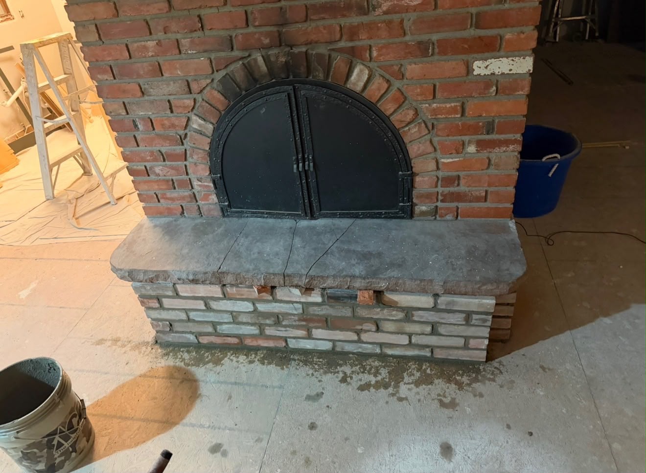 Rebuilt brick fireplace hearth base with fresh mortar and stone cap after repair